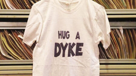 white tshirt from the lesbian herstory archives that says "hug a dyke"